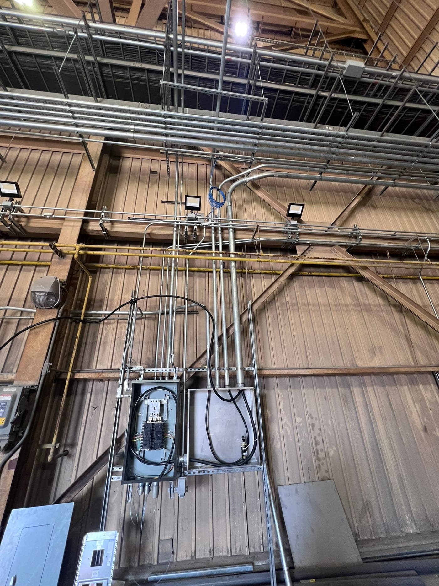 Rigid conduit runs and LED high-bay lighting installed in an industrial building