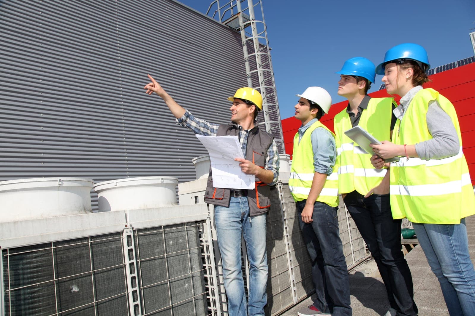 Project team reviewing drawings on a rooftop mechanical platform