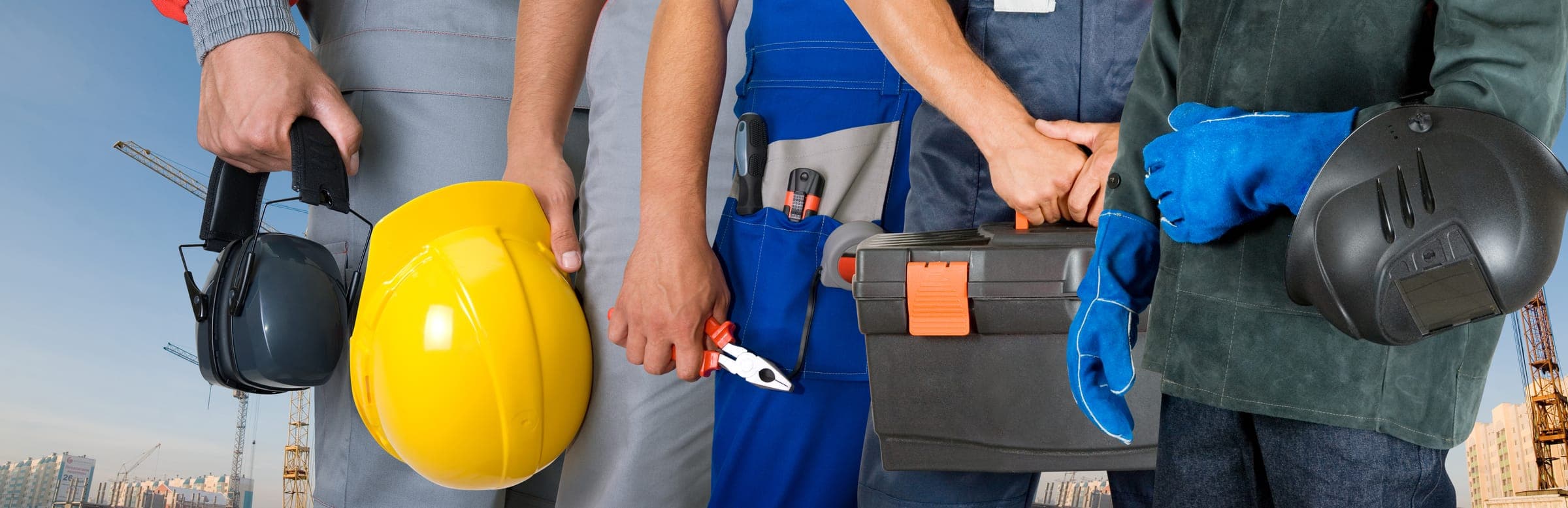 Workers holding hard hats, hearing protection, gloves, and other personal protective equipment
