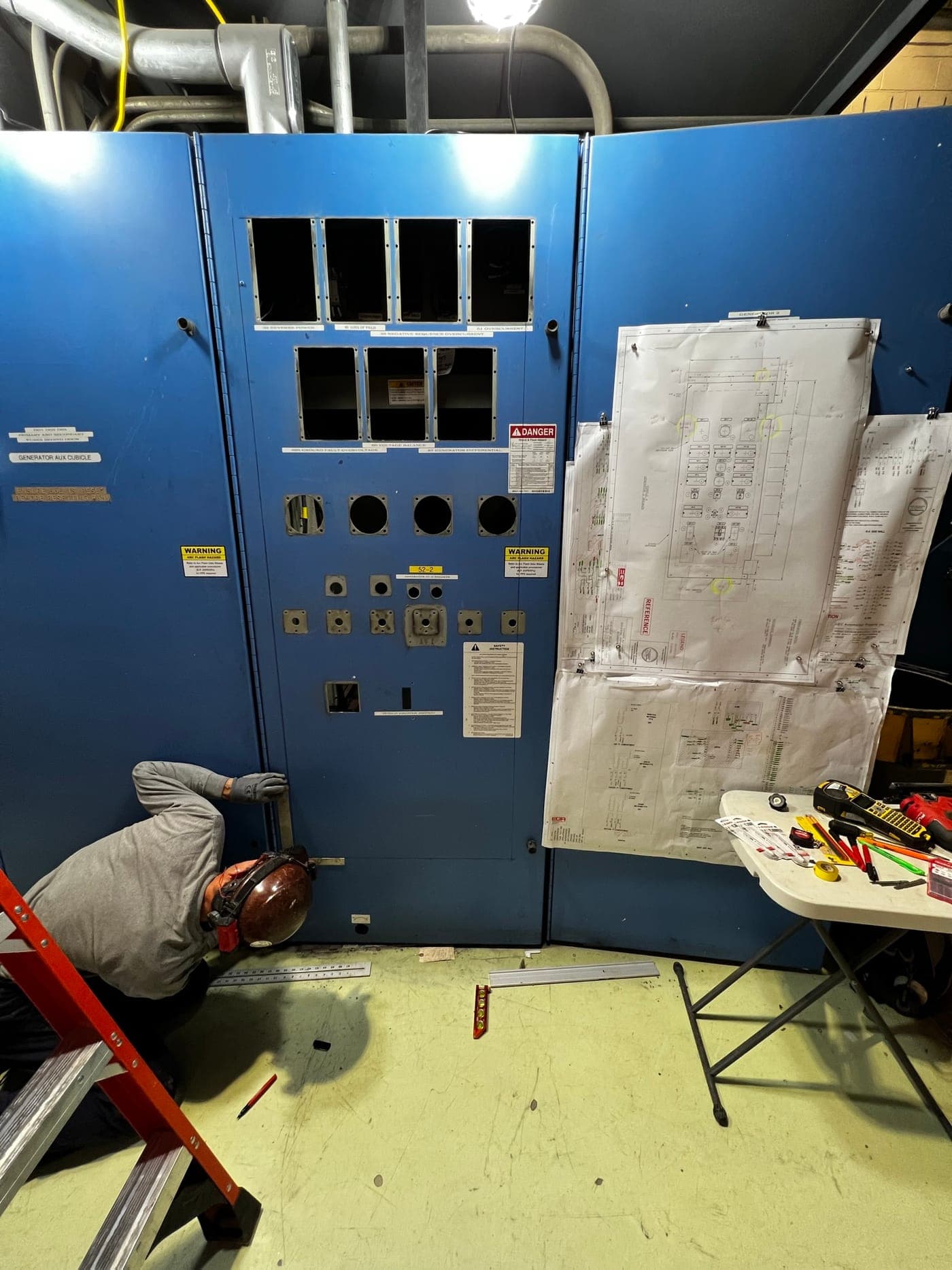 Electrician working from engineered drawings during a switchgear retrofit