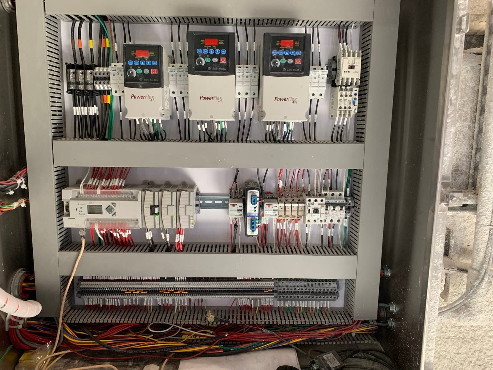 Control panel with three variable frequency drives and a PLC, wired and labeled by Electrisource